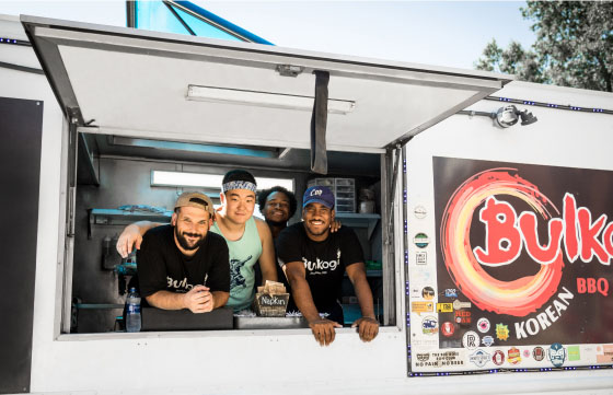 Food truck employees smiling out of the serving window.