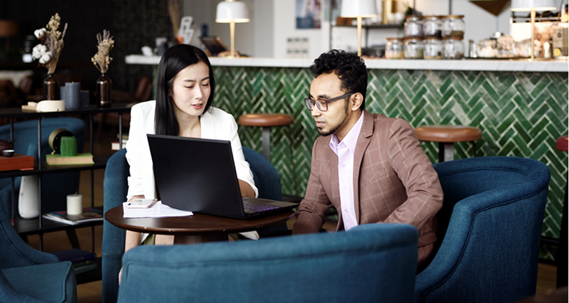 Colleagues looking at a laptop in a cafe.
