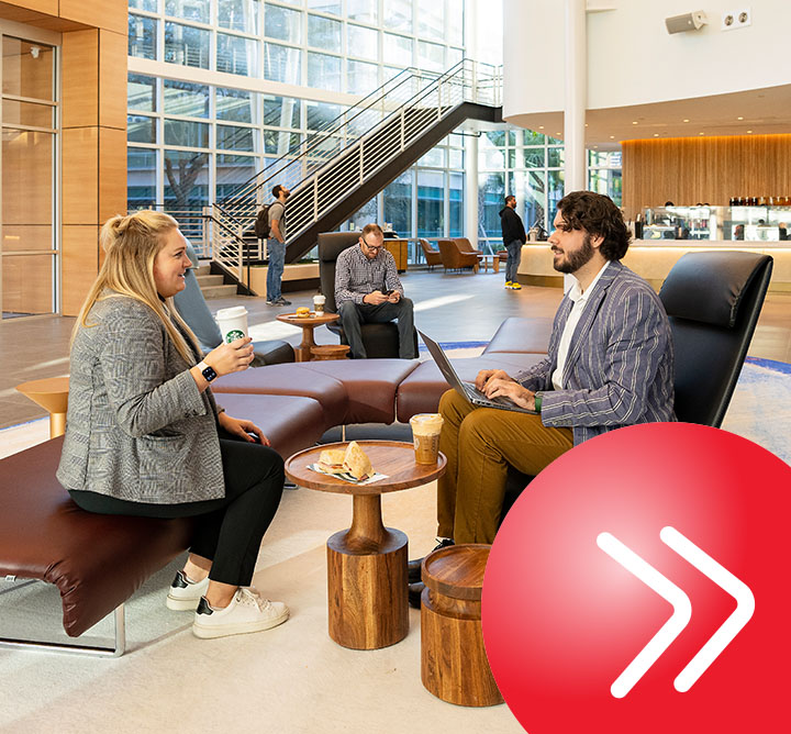Two professionals having a lunch meeting and drinking coffee in the lobby of an office building.