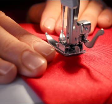 Hands guiding a piece of fabric through a sewing machine.