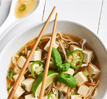 A bowl of ramen with tofu and vegetables.