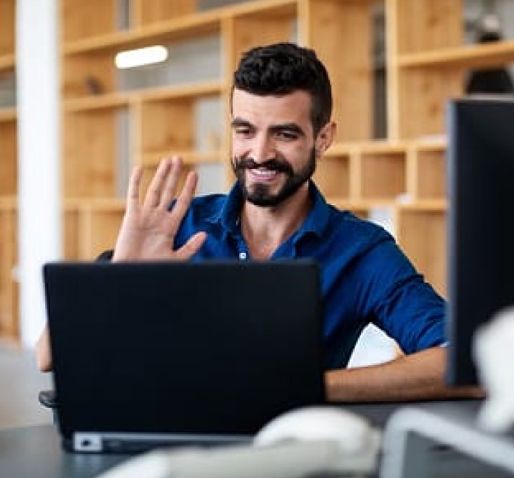 Man waving to computer screen.