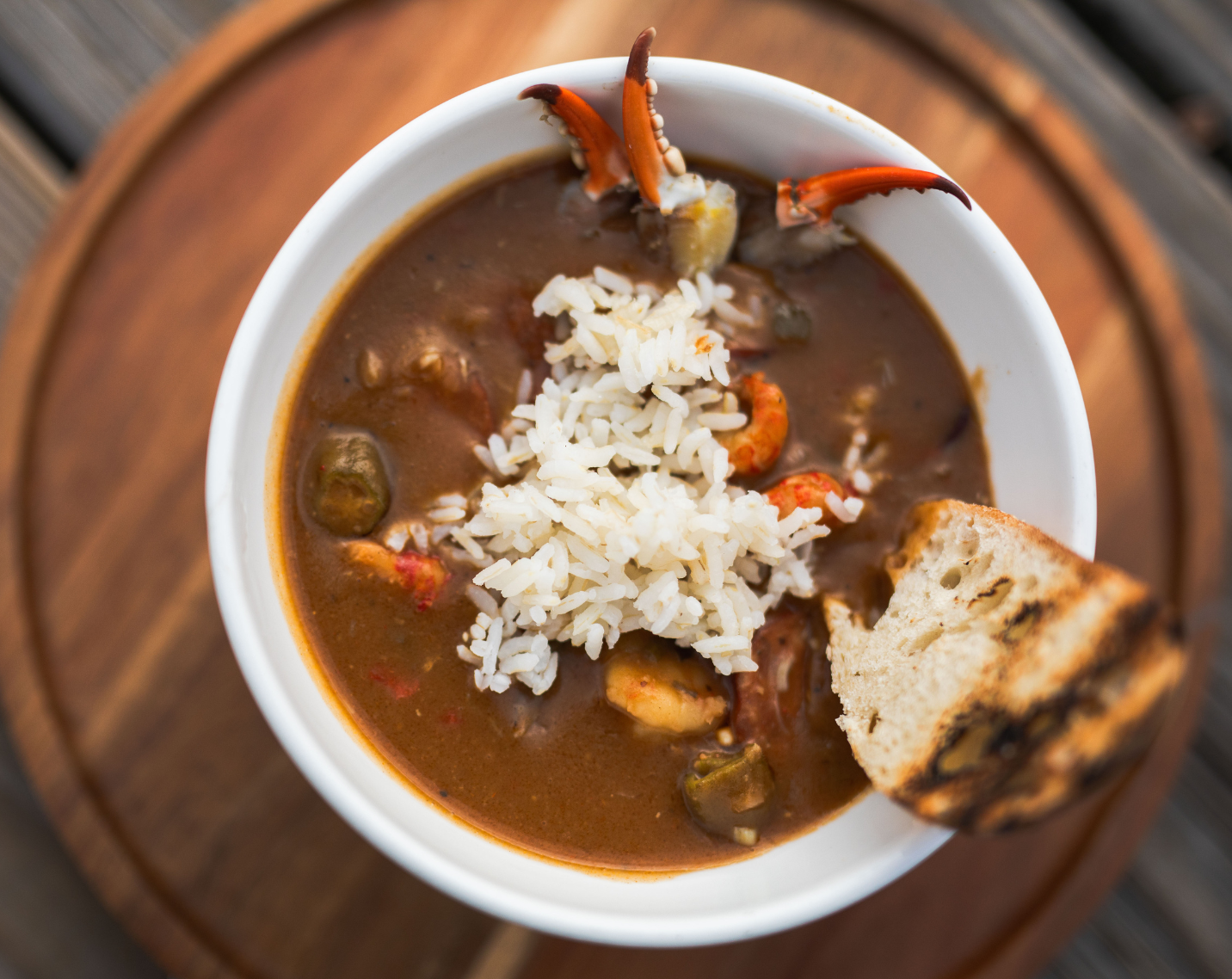 Louisiana-Style Seafood Gumbo with rice, grilled baguette, sassafras, cocktail crab claws, oysters, crawfish tails, and andouille sausage.