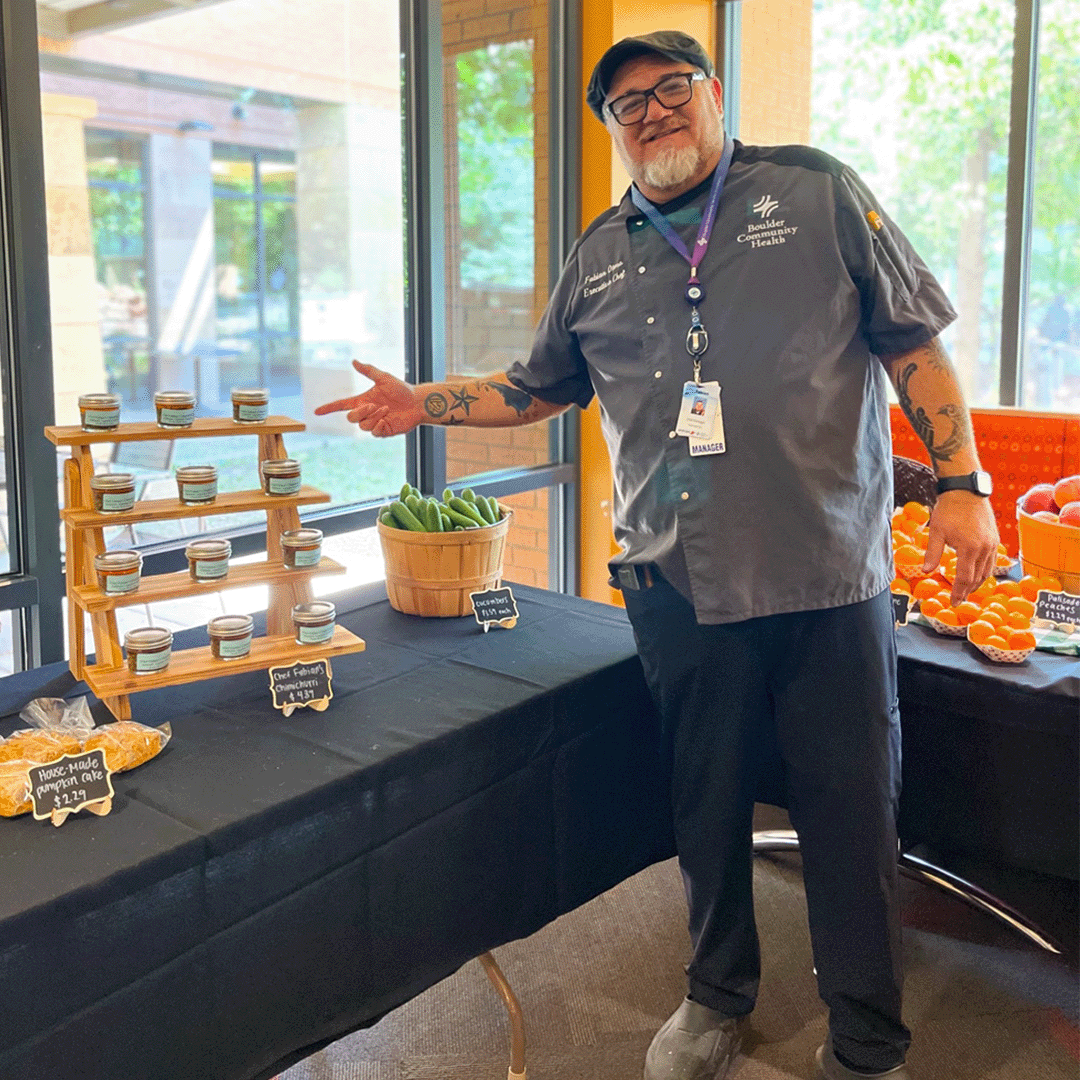 A chef poses next to a farmer's market stand item he created.