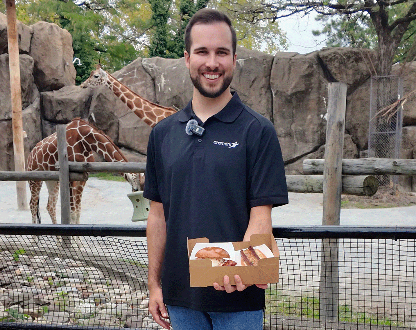 conall smith holidng a box of food with giraffes in the background