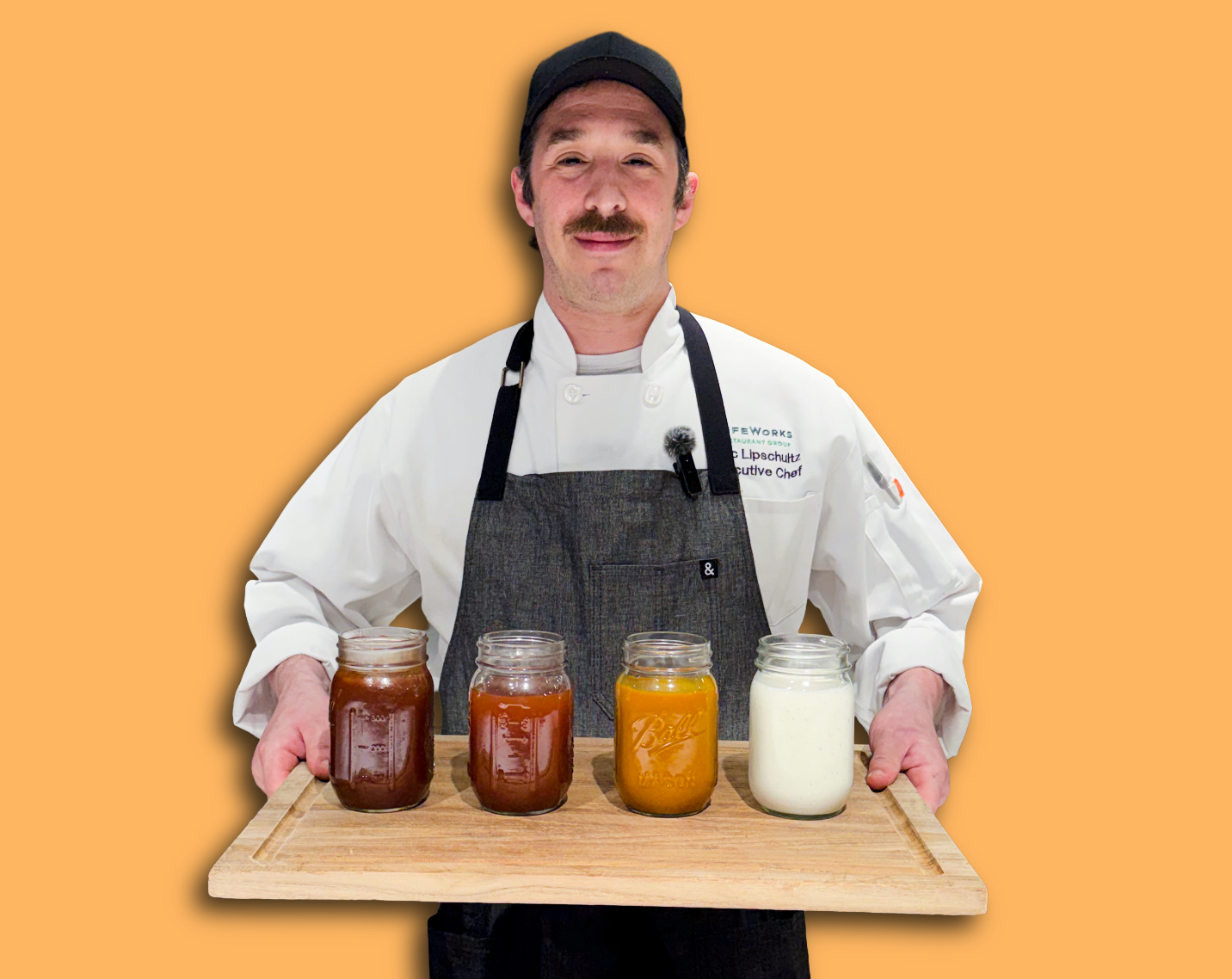 chef alec holding a tray of bbq sauces