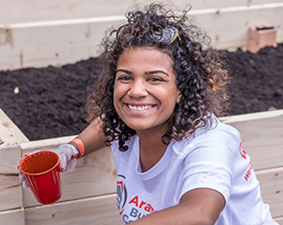 An Aramark volunteer taking a break from gardening work.