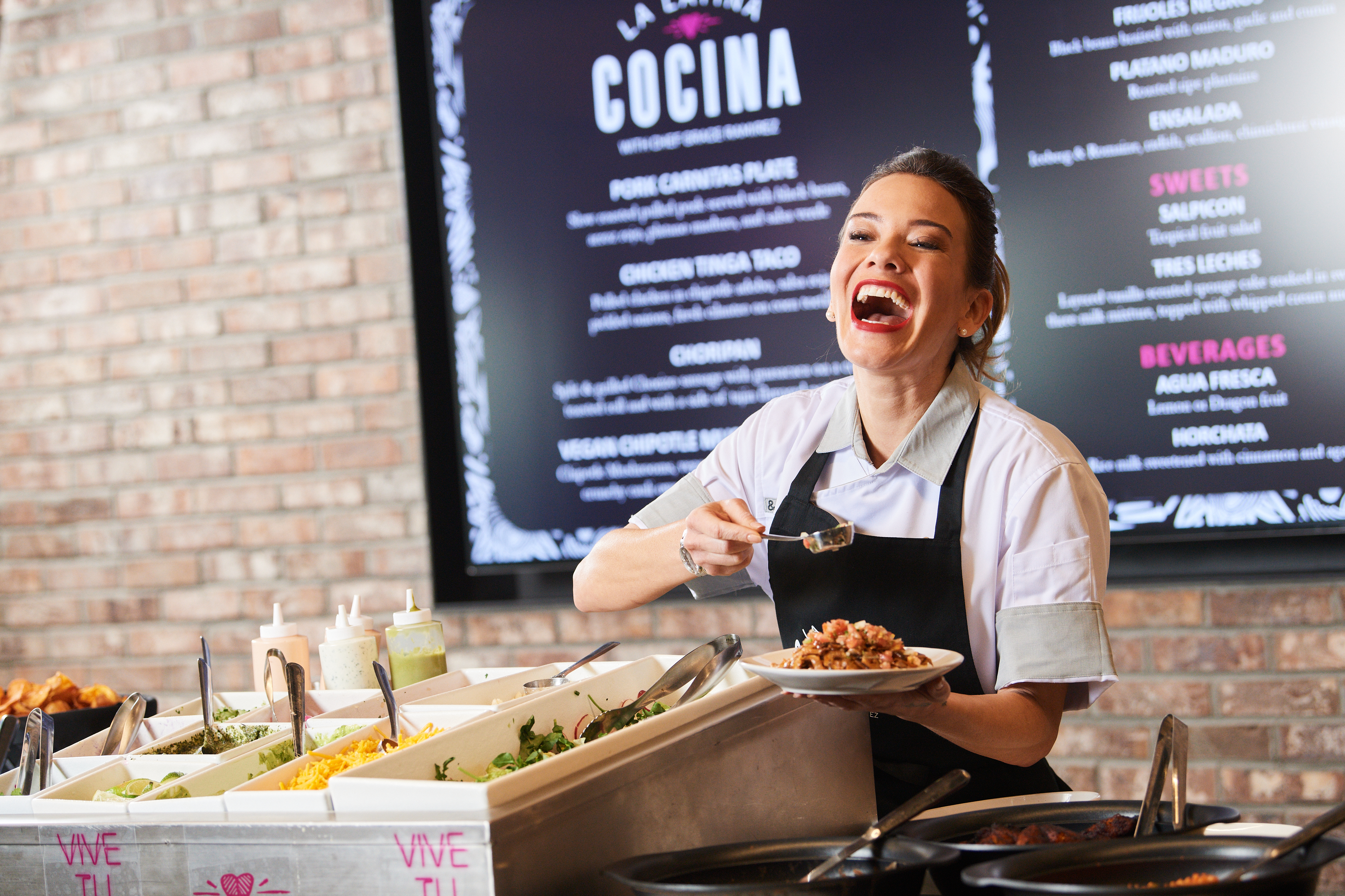 Grace Ramirez laughing while serving food at her restaurant, La Latina Cocina.