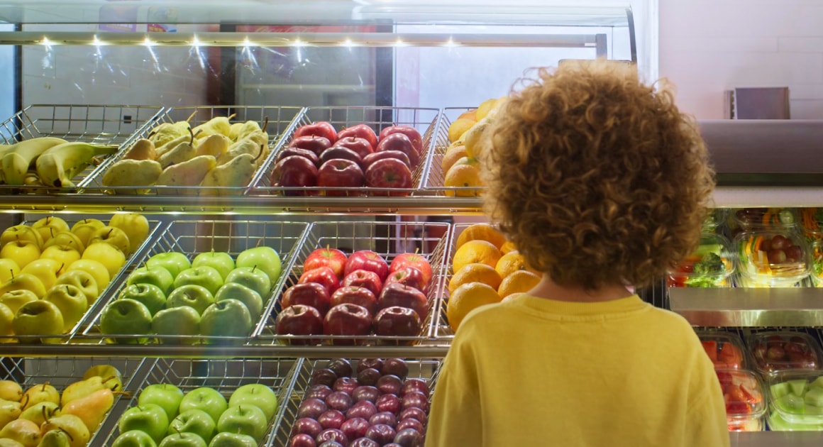 A child looking at a display of fresh fruit at a food market.