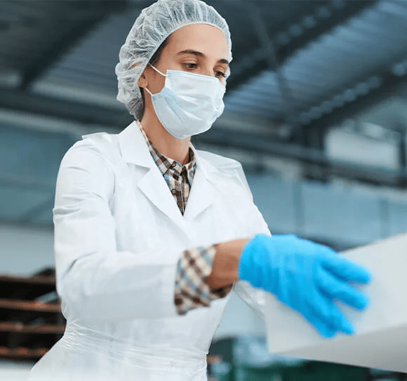 Person wearing mask and gloves holding a white cake box