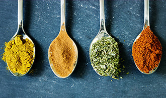 A row of spoons holding different spices.