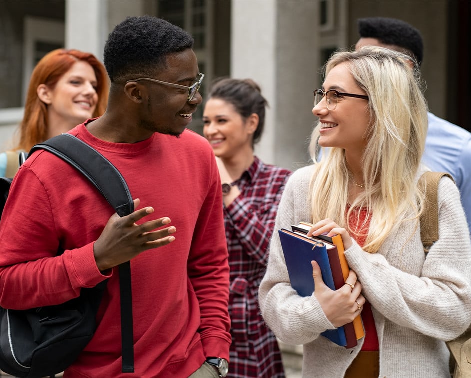 Smiling students outside of an academic building.