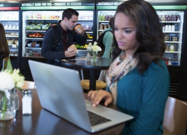 A student sitting in a cafeteria and using her laptop.