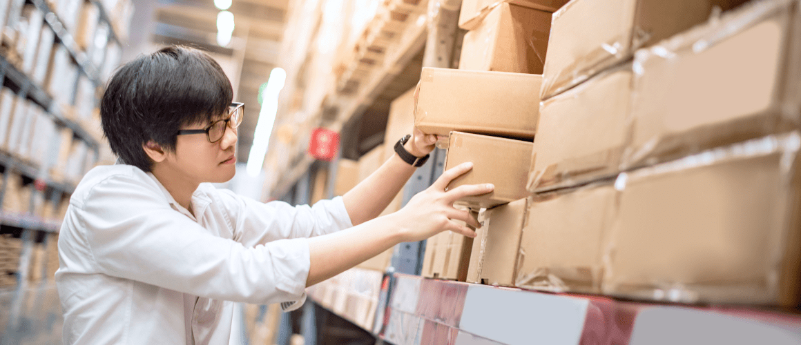Worker organizing boxes in a warehouse.