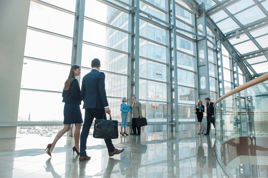 Business people walking in glass-enclosed lobby