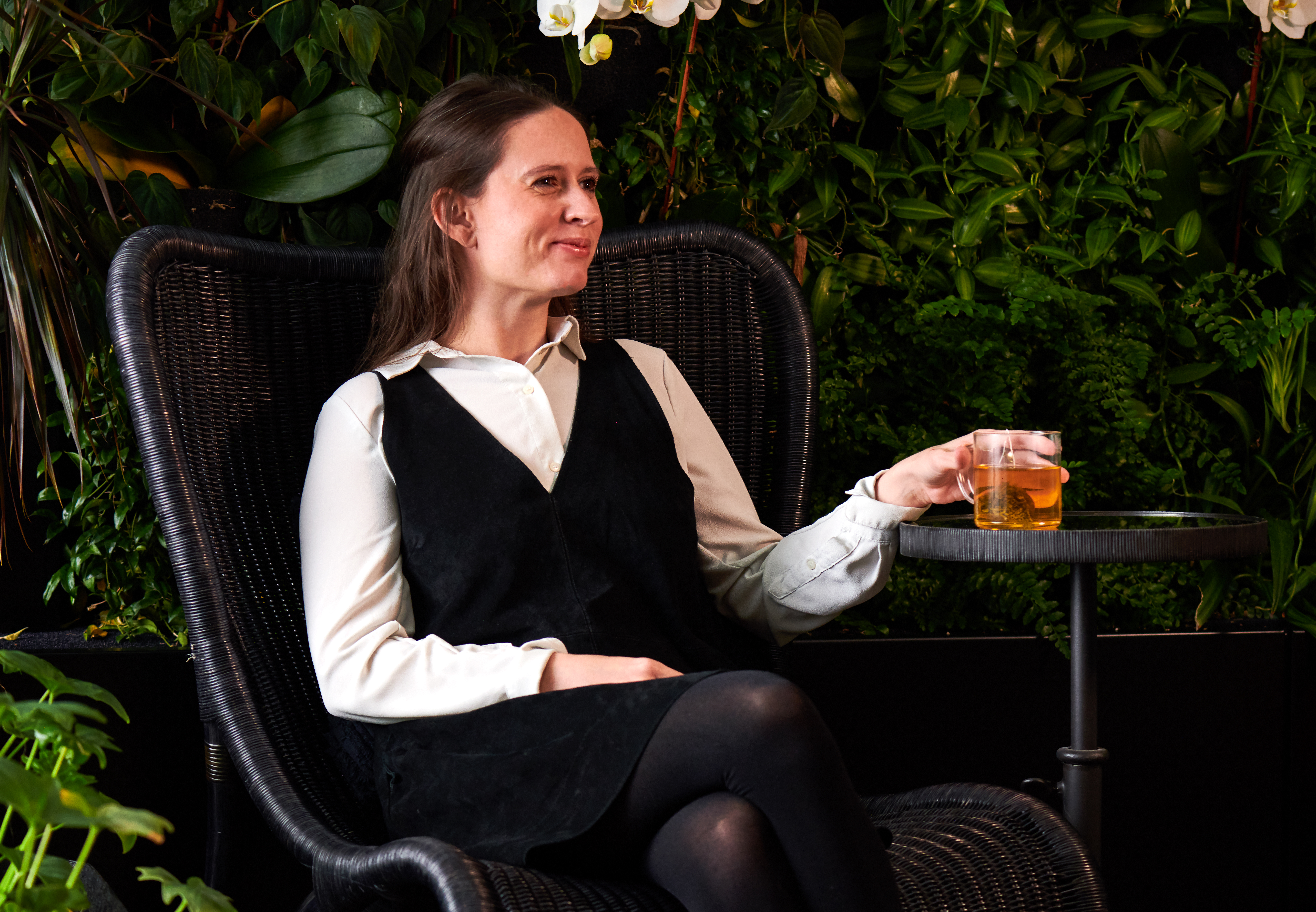 Woman sitting in a chair smiling with a drink