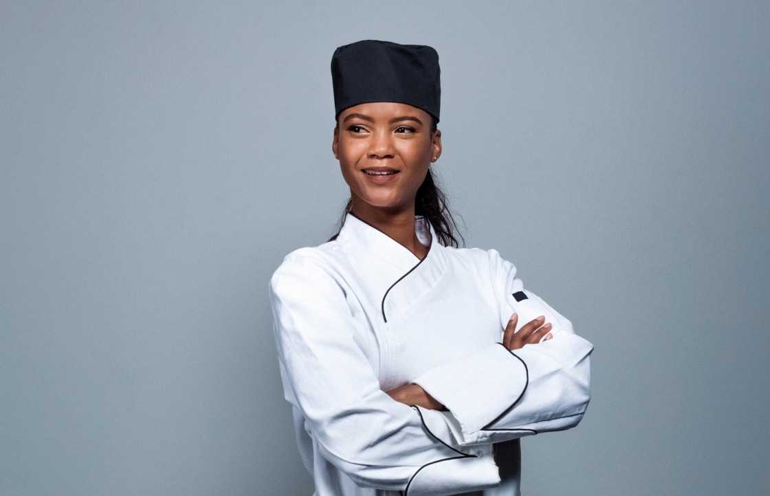 A female chef standing with her arms crossed.
