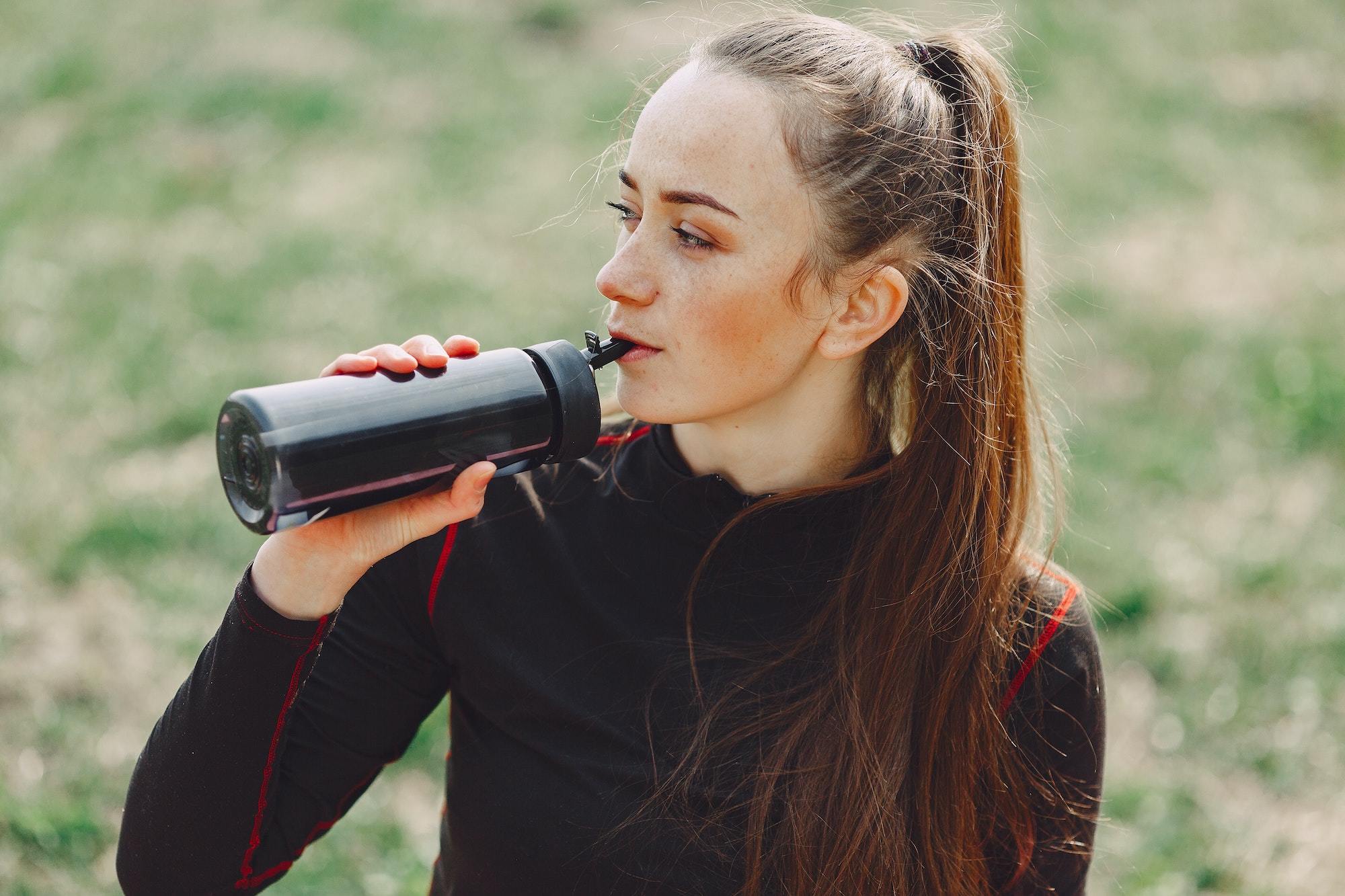 A student drinking from a black water bottle.