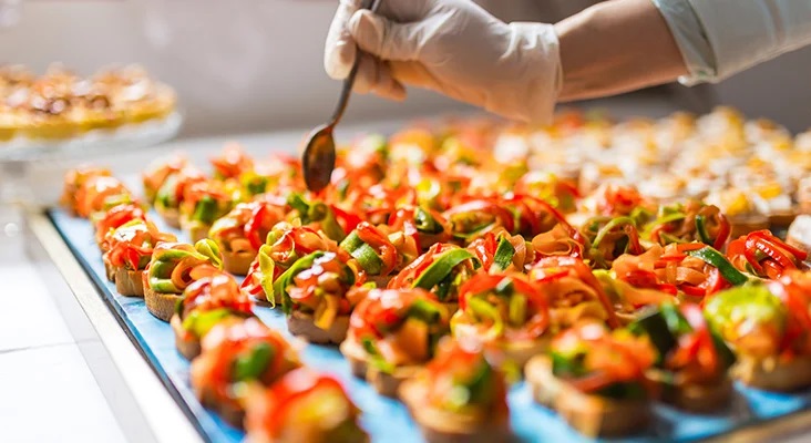 Chef preparing a tray full of elaborate hors d'oeuvres.