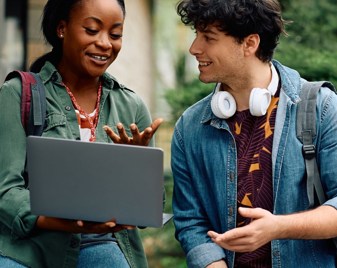 Students chatting on campus with a laptop.