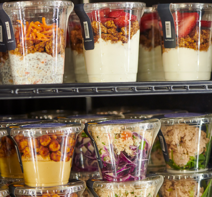 Grab-and-go food cups on a refrigerated shelf.