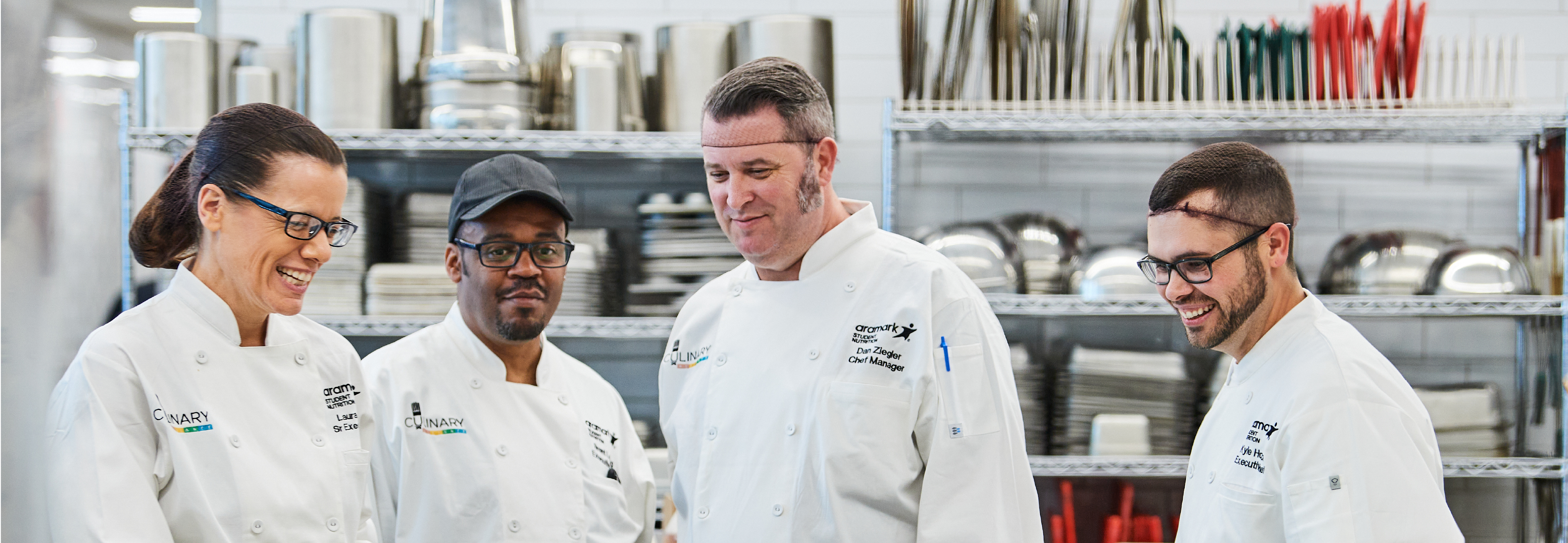 Smiling Aramark chefs wearing food safety supplies.