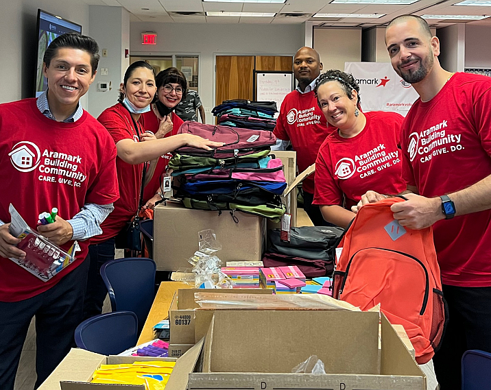 Aramark employee volunteers filling backpacks with school supplies for charity.