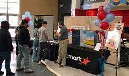 Students looking at an Aramark display table with posters and balloons.