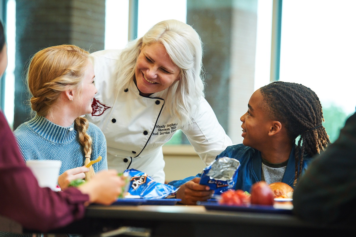 Chef talking to students at a lunch table.