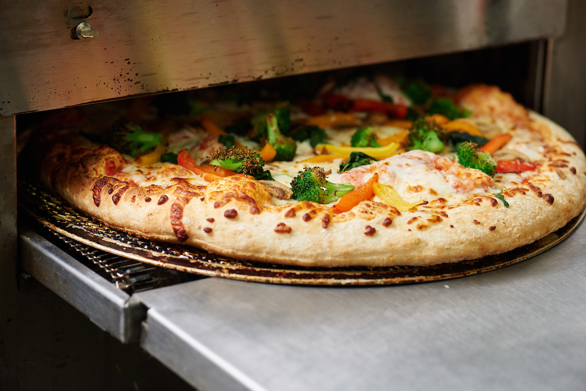 Pizza being put into an oven.