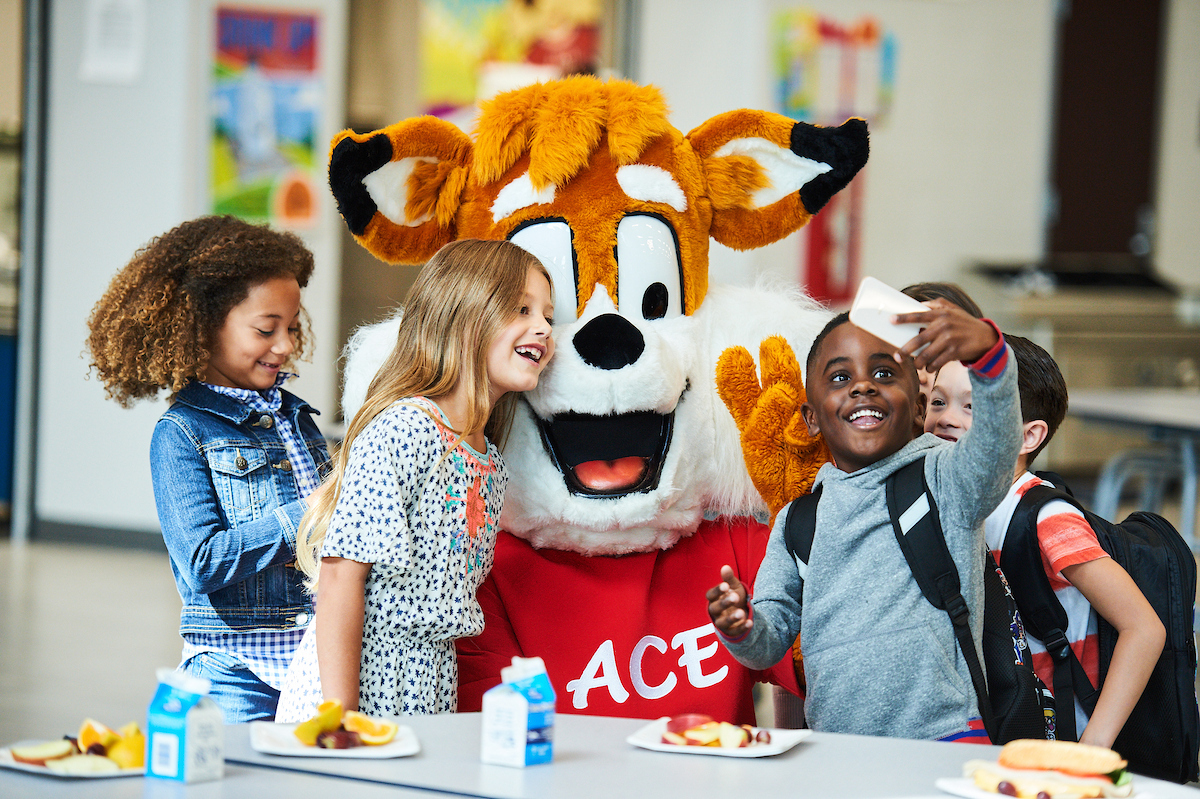 Young children taking a selfie with ACE the mascot.