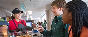 Students paying for lunch in a school cafeteria.