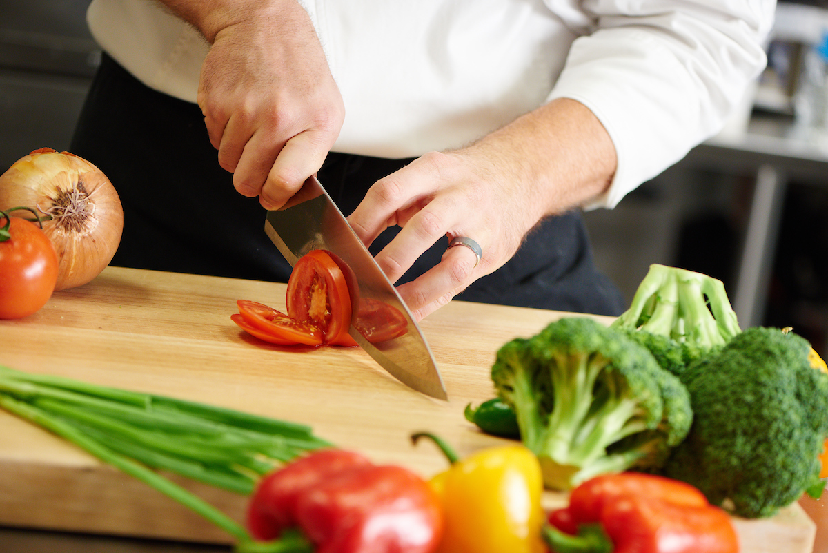 A chef chopping up vegetables on a cutting board.