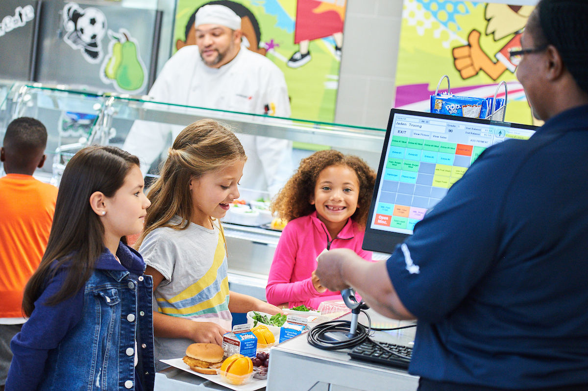 Young students in line at a cash register.