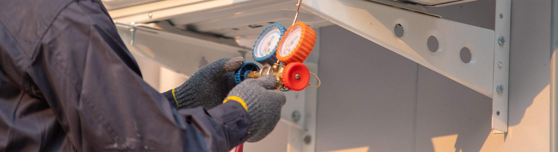 A worker wearing protective gloves checks the gauges on a device.