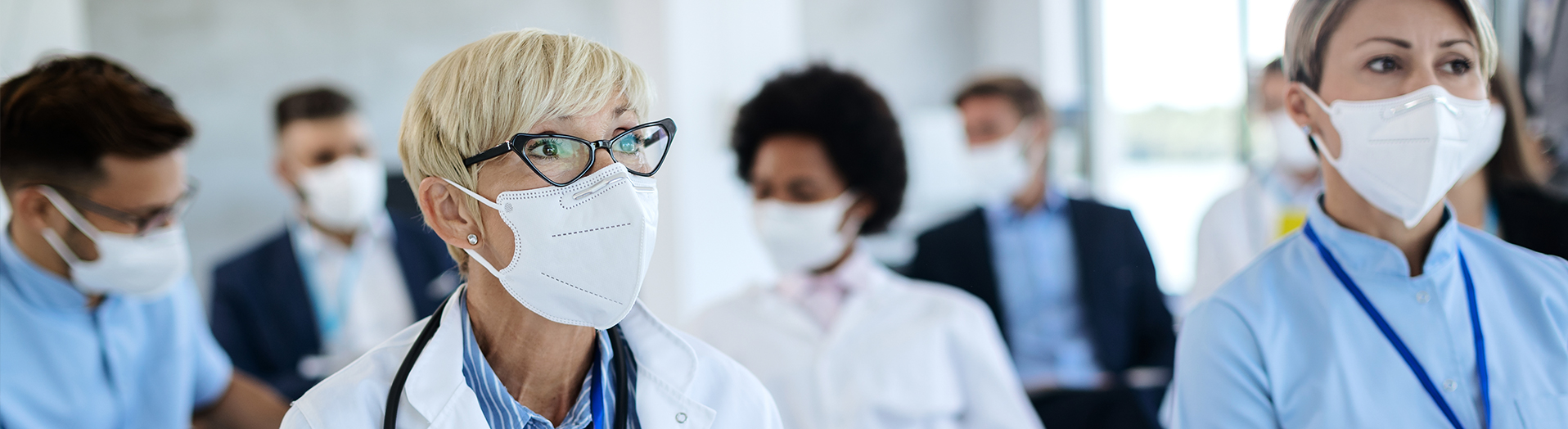 Masked healthcare providers sitting watching a presentation.
