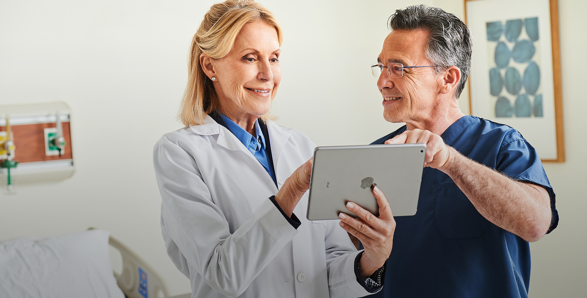 A doctor and nurse discussing the information on a tablet screen.
