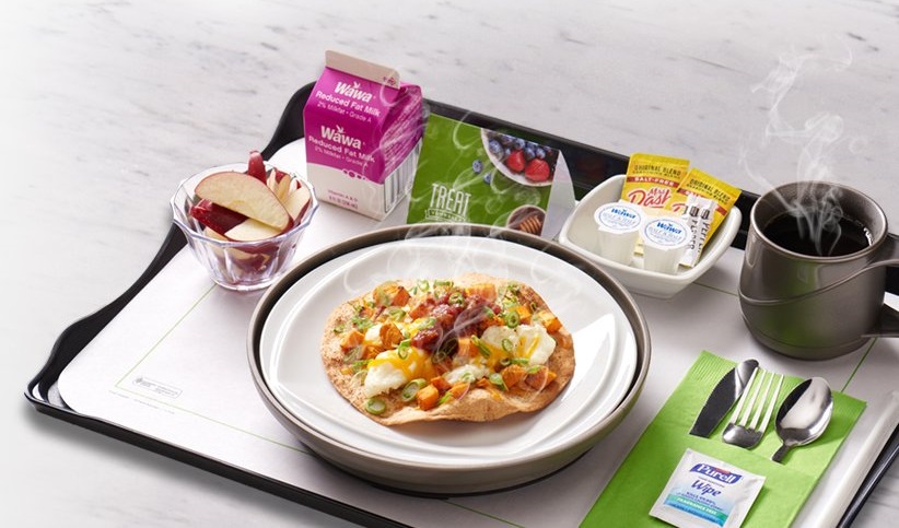 A tray with a breakfast wrap, apple slices, milk, and coffee.