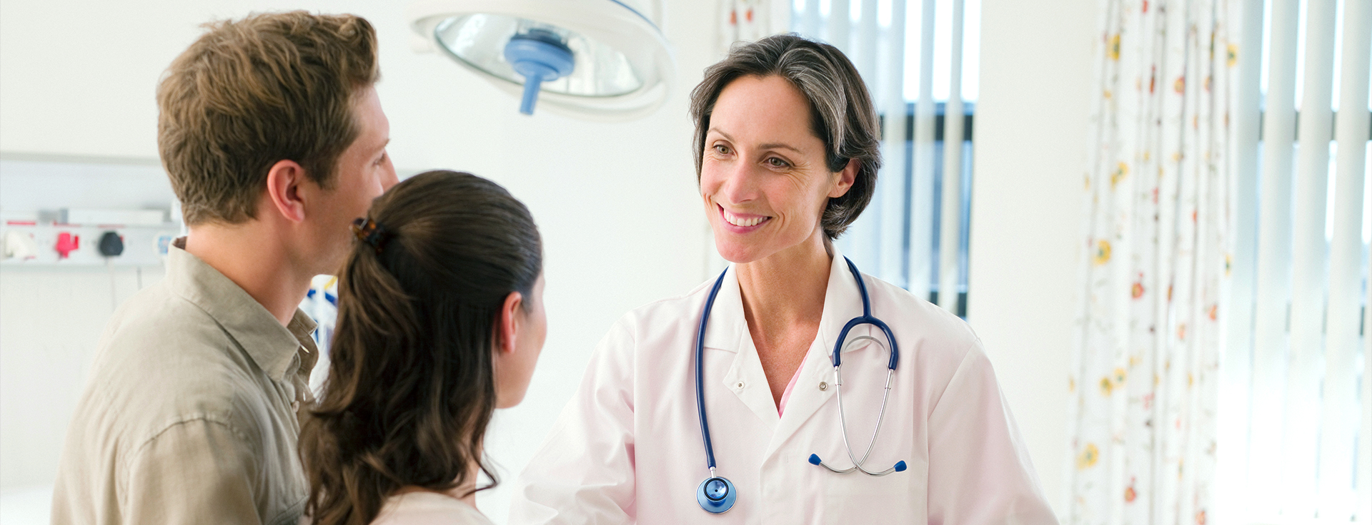 A doctor talking to a couple in an exam room.