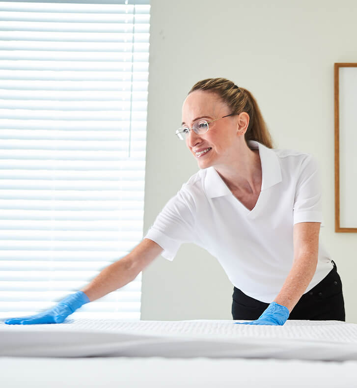A hospital employee changing the bedsheets of a hospital bed.