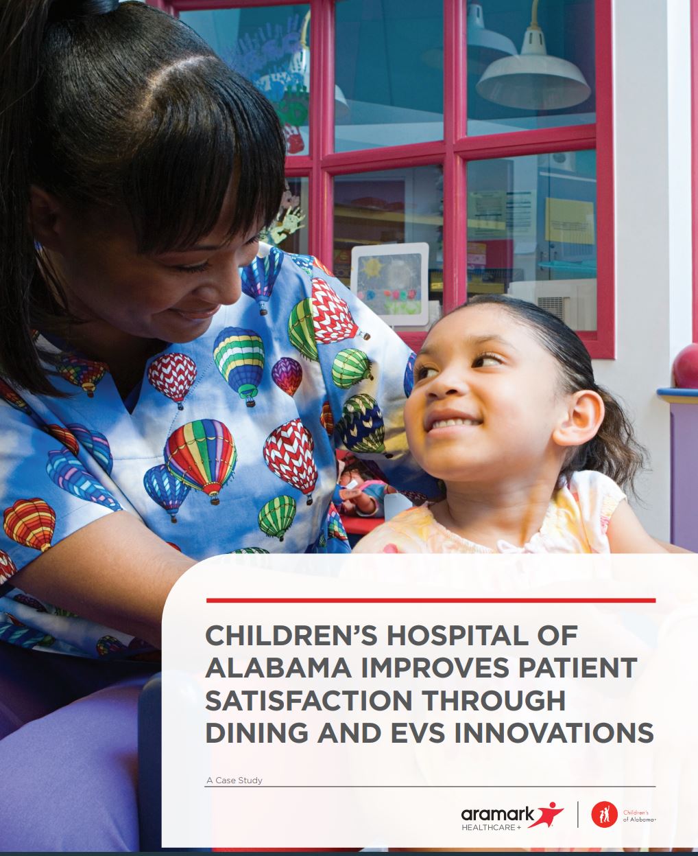 A young patient smiles looking back at a nurse in colorful scrubs.