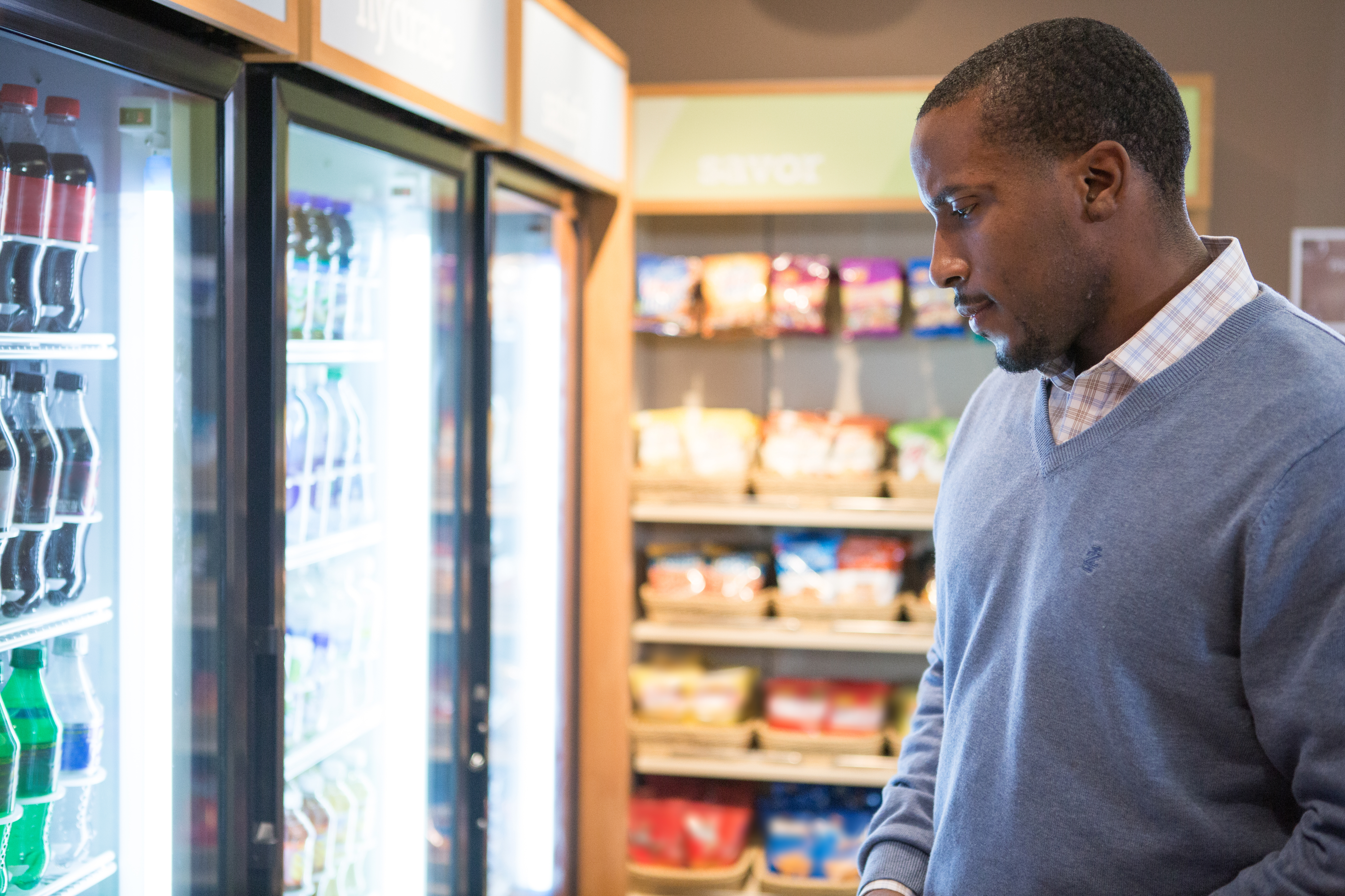 Man looking at a cooler of drinks in a store 