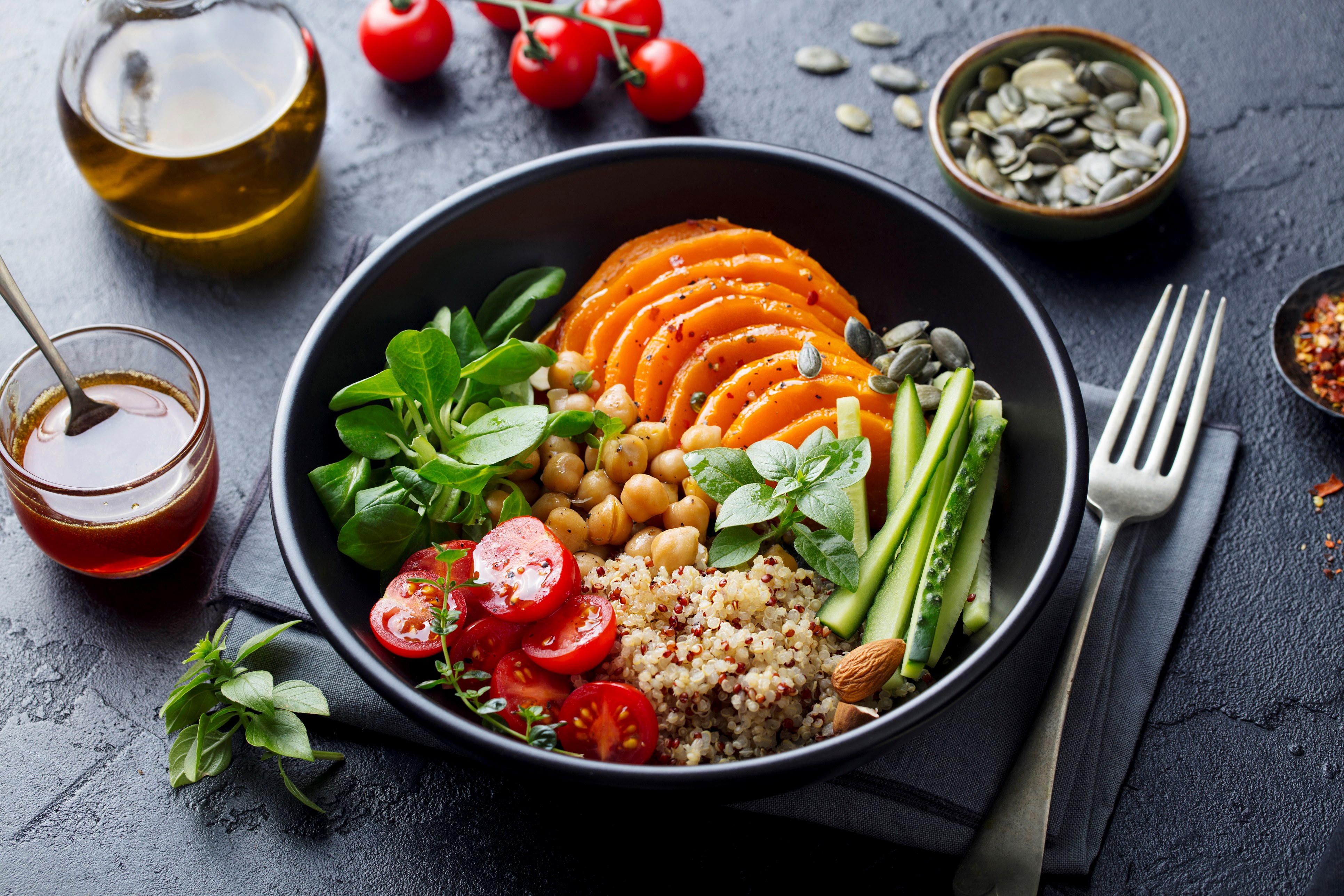 A quinoa bowl with various vegetables and herbs.