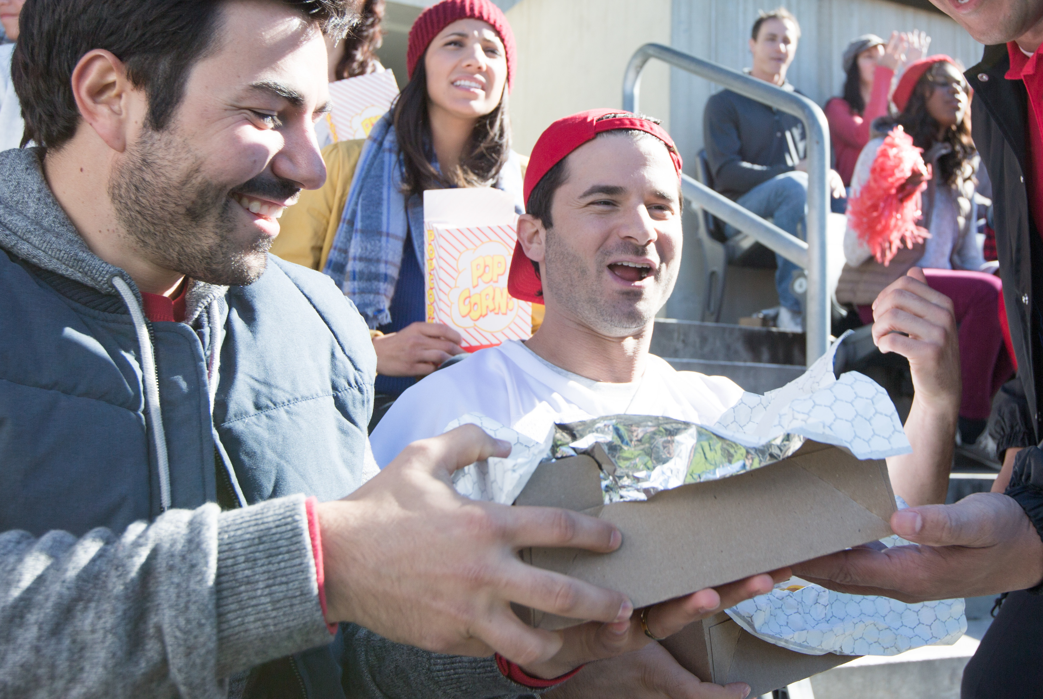 two men cheering with stadium food