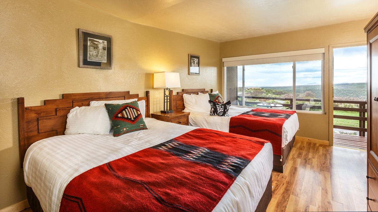 A hotel room with a large window overlooking a forest.