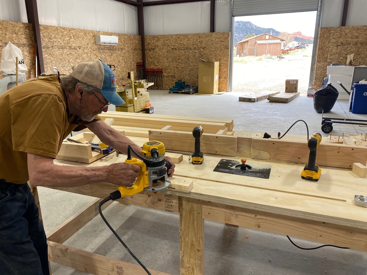 A worker using a construction tool on a block of wood in a workshop.