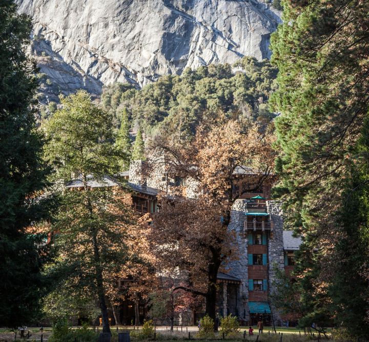 A large stone lodge set among the trees and mountains.