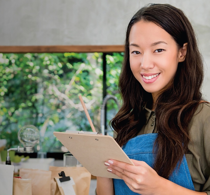 Business owner standing at a coffeeshop window with a clipboard.