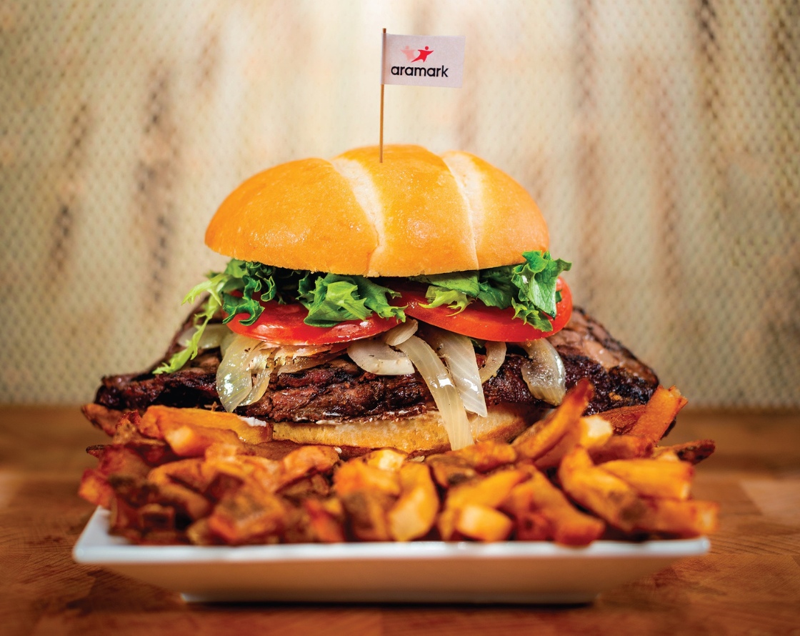 Plated sandwich and fries with an Aramark toothpick flag.